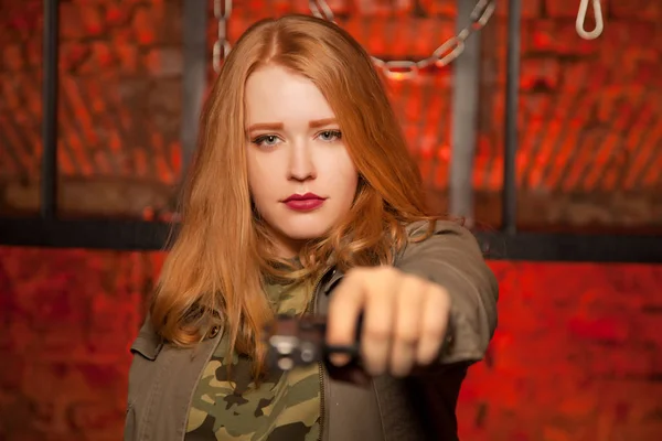 美丽的年轻 Red Haired 女孩与枪在红色砖墙单独 — 图库照片