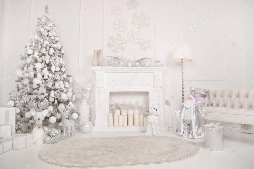 christmas frozen snow tree with gifts near the fireplace and cozy sofa in the white room