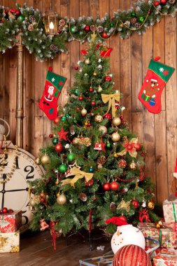 Kırmızı ve Altın süslemeleri, büyük saat ve altında hediyeleri ile yeşil Noel ağacı ile güzel rahat kahverengi Oda. kimse.