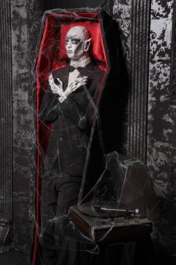 tabut bir adam siyah sıva ile siyah bir odada duvarın yanında ayakta ölü kukla ile