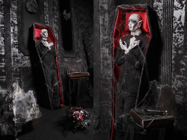 tabut bir adam siyah sıva ile siyah bir odada duvarın yanında ayakta ölü kukla ile