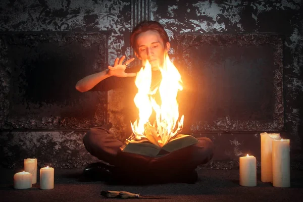 skinny Gothic necromancer sorcerer performs a ritual by burning magic books and uttering powerful spells, one in the night