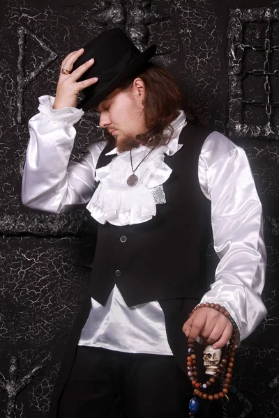 a dangerous warlock in the black historical clothing with a hat and white lace shirt stands in the background of dark black sorcery runic gate