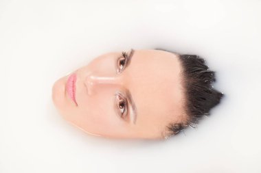 güzel esmer kız süt ile dolu bir küvet içinde yatan rahatlatır ve zevk alır