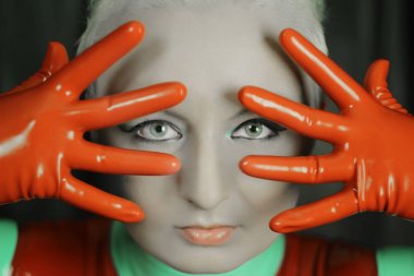 sevimli kısa saçlı sarışın kız lateks catsuit ve kauçuk kırmızı eldiven, karanlık bir arka plan üzerinde yalnız poz