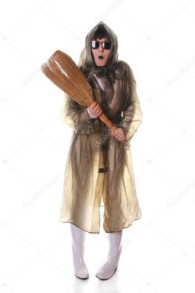 truly strange old lady playing and posing in transparent retro cloak and rubber boots with broom on white background isolated alone