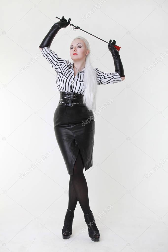 cruel fetish fashion mistress woman standing with bdsm riding crop alone on white background
