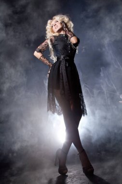 kabarık beyaz uzun saç ve uzun bacakları kısa siyah dantel elbise duman ışık ile karanlık sahne arka plan üzerinde poz ile lüks sarışın