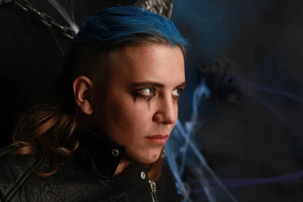 Teenager alt Junge mit blauen Haaren und rasiertem Kopf, schwarz gekleidet auf dunklem Hintergrund — Stockfoto