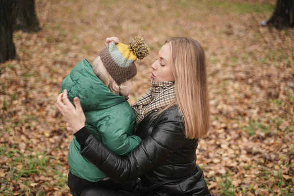 Mom wears a hat to a child on the street. Portrait of cheerful little baby having fun with trendy mom outdoor — Stock Photo, Image