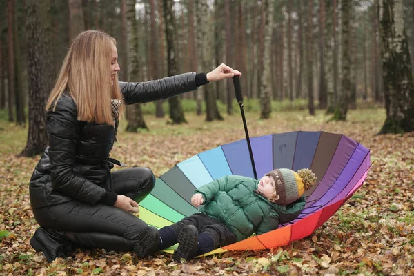 Uma bela mãe caucasiana e criança pequena se divertindo no outono Park, andando com guarda-chuva — Fotografia de Stock