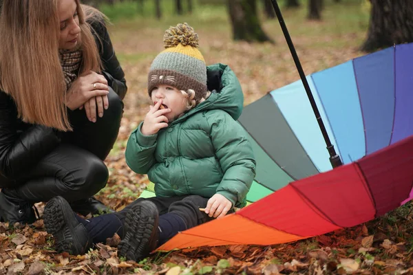 Une belle mère caucasienne et un petit enfant s'amusent dans le parc d'automne, marchant avec un parapluie — Photo