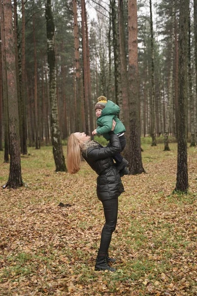 Belle mère caucasienne et petit enfant s'amusant dans le parc d'automne, à pied. mère tient l'enfant dans ses bras — Photo