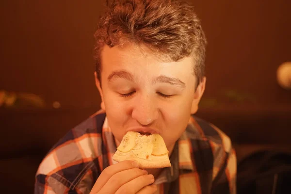 Tiener jongen eet pizza en geniet ervan, closeup genieten en genieten. — Stockfoto
