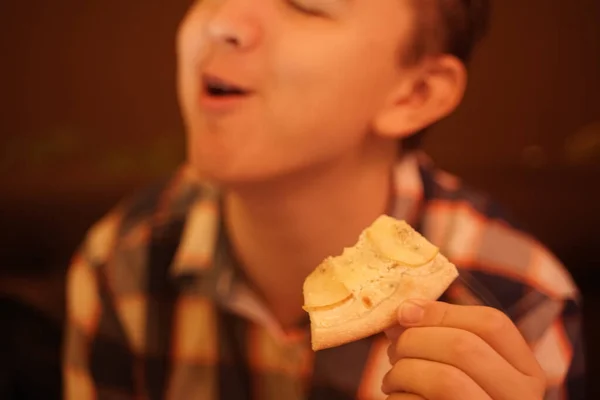 Adolescente menino come pizza e gosta dele, close-up desfrutando e saboreando . — Fotografia de Stock