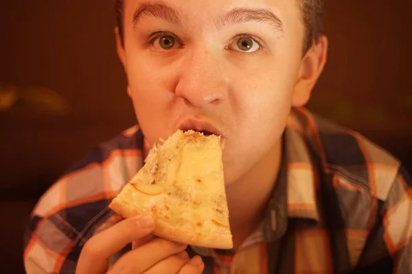 Genç çocuk pizza yer ve bundan zevk alır. Yakından zevk alır.. — Stok fotoğraf