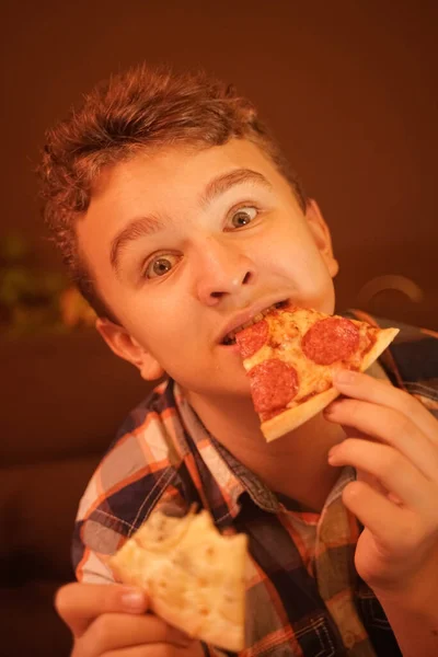 Tiener jongen eet pizza en geniet ervan, closeup genieten en genieten. — Stockfoto