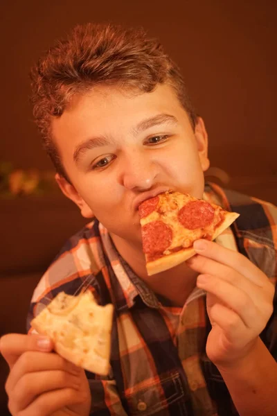 Adolescente menino come pizza e gosta dele, close-up desfrutando e saboreando . — Fotografia de Stock