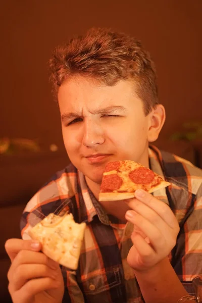 Adolescente chico come pizza y disfruta de ella, primer plano disfrutando y saboreando . — Foto de Stock