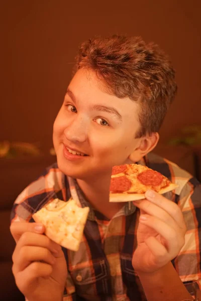 Tiener jongen eet pizza en geniet ervan, closeup genieten en genieten. — Stockfoto