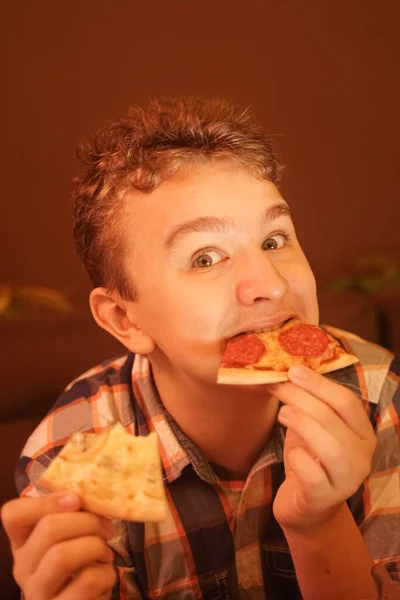 Tiener jongen eet pizza en geniet ervan, closeup genieten en genieten. — Stockfoto