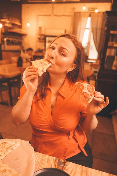 Bonita mujer caucásica más tamaño saboreando y disfrutando de la pizza en la pizzería — Foto de Stock