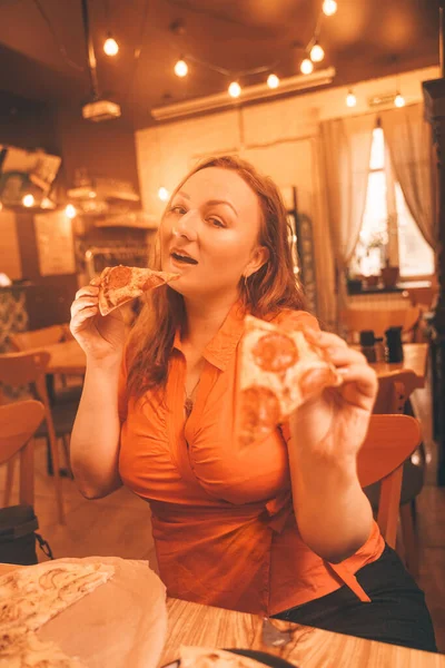 Bonita mujer caucásica más tamaño saboreando y disfrutando de la pizza en la pizzería — Foto de Stock