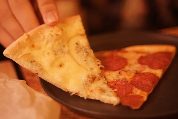 Tabakta iki farklı lezzetli ev yapımı pizza. İnsanların elleri pizza alır.. — Stok fotoğraf