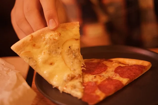 Tabakta iki farklı lezzetli ev yapımı pizza. İnsanların elleri pizza alır.. — Stok fotoğraf