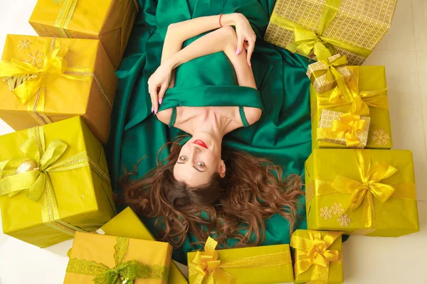 Top view of beautiful slender fashion woman in trendy green dress lying with golden boxes with gifts. cheerful girl ready to celebrate christmas. — Stock Photo, Image