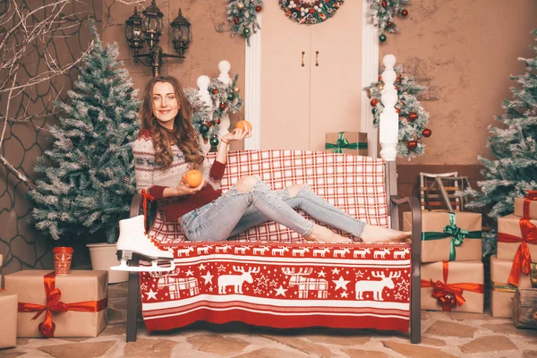 Encantadora chica delgada en vaqueros de moda bordados con perlas y suéter de Navidad descalzo sentado en un banco, cuerpo de cuerpo entero — Foto de Stock