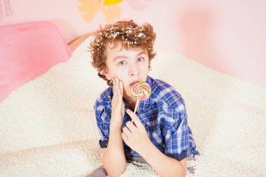 Havuzda köpüklü, küçük beyaz topları olan genç bir çocuk. Rahatlama terapisi gören biri. Pembe arka planda renkli lolipopu olan beyaz bir çocuk..