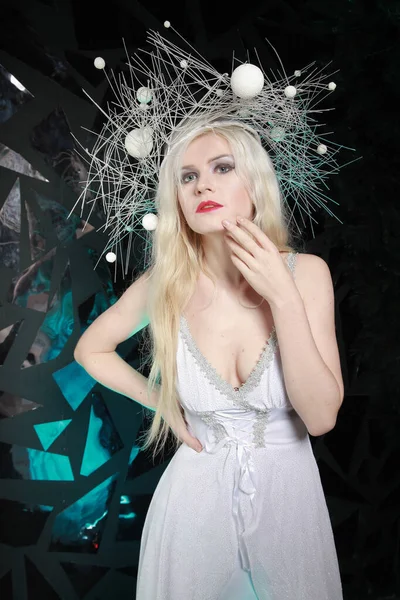 Hot strange slender woman with long blonde hair wearing white dress and unusual hat on black background alone — ストック写真