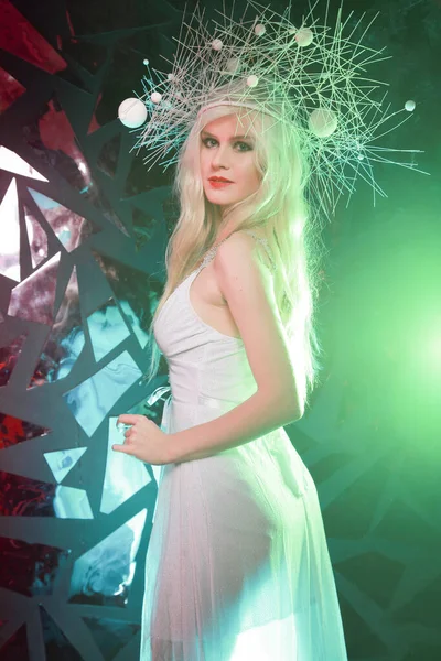 Hot strange slender woman with long blonde hair wearing white dress and unusual hat on black background alone — ストック写真