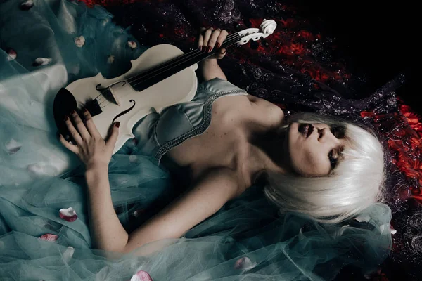 Молодая блондинка с белой фиалкой ночью лежит на кровати — стоковое фото
