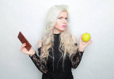 Çekici, formda bir kız çikolata ya da elma yemek için hava durumunu değerlendirir. Kötü ve iyi yemek..