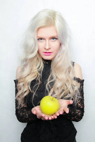 Joven mujer bonita en un vestido negro de moda con manzana verde sobre fondo blanco en el estudio — Foto de Stock