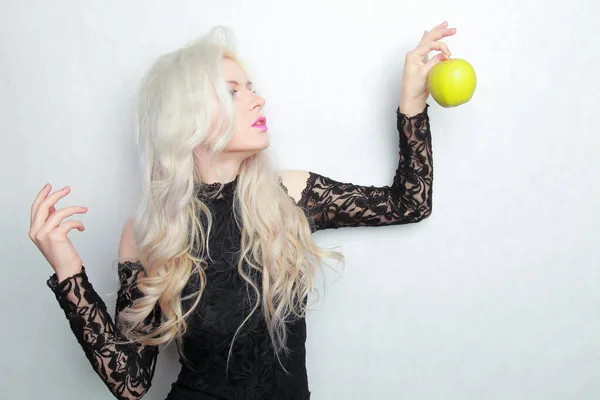 Joven mujer bonita en un vestido negro de moda con manzana verde sobre fondo blanco en el estudio — Foto de Stock