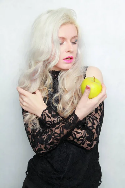 Joven mujer bonita en un vestido negro de moda con manzana verde sobre fondo blanco en el estudio — Foto de Stock