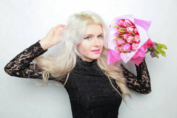 Něžná hezká blondýnka štíhlé teen dívka s růžovými květy. veselá žena s čerstvou kyticí — Stock fotografie