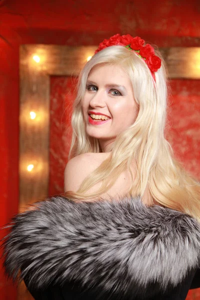 Jong mode blond dame dragen bont outfit poseren op rood mode achtergrond met lamp bollen frame — Stockfoto