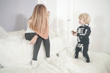 Anne ve oğul içeride lezzetli çöreklerle eğleniyorlar. Cadılar bayramı iskelet kostümlü çocuk güzel annesiyle oynuyor..