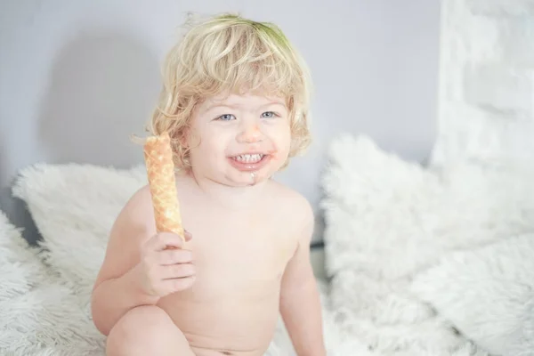 Klein kind nemen wafel en eten met plezier en plezier op witte kamer achtergrond — Stockfoto