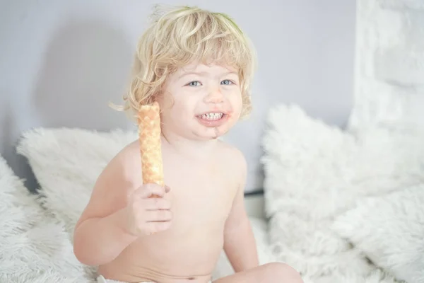 Klein kind nemen wafel en eten met plezier en plezier op witte kamer achtergrond — Stockfoto