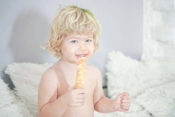 Klein kind nemen wafel en eten met plezier en plezier op witte kamer achtergrond — Stockfoto