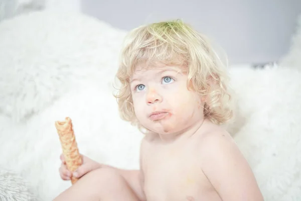 Klein kind nemen wafel en eten met plezier en plezier op witte kamer achtergrond — Stockfoto