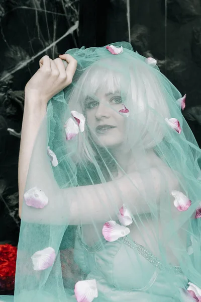Söt blond flicka i blå slöja med blomma hängen på mörk bakgrund — Stockfoto