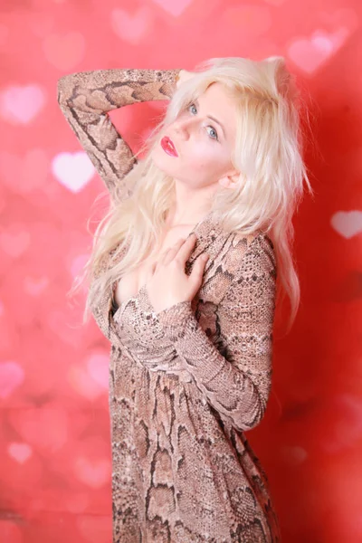 Mooie vrouw met blond haar poseren op rode studio achtergrond — Stockfoto