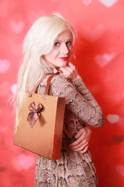 Blond jong meisje met gift box op rood achtergrond alleen — Stockfoto