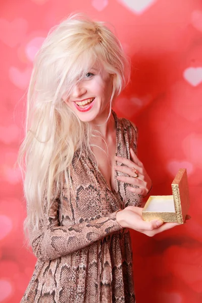 Feminino segurando uma caixa com um anel no fundo do estúdio vermelho — Fotografia de Stock